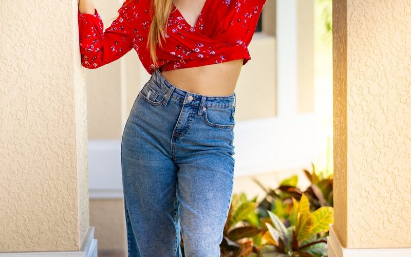 woman wearing sun hat, red crop top, and blue jeans