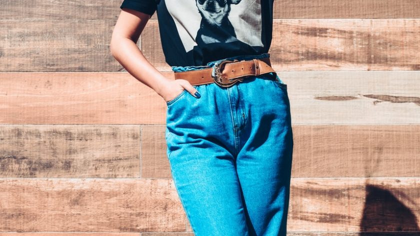 woman in black and white t-shirt and blue denim jeans standing on brown wooden floor