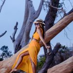 woman in yellow dress climbing on brown tree during daytime