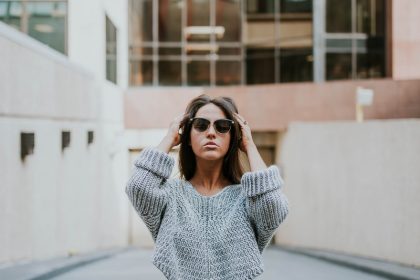 woman in grey knit shirt standing on roadway during daytime