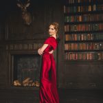 woman in red long sleeve dress standing beside brown wooden book shelf
