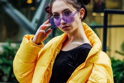 woman in yellow jacket with black inner shirt wearing purple sunglasses during daytime