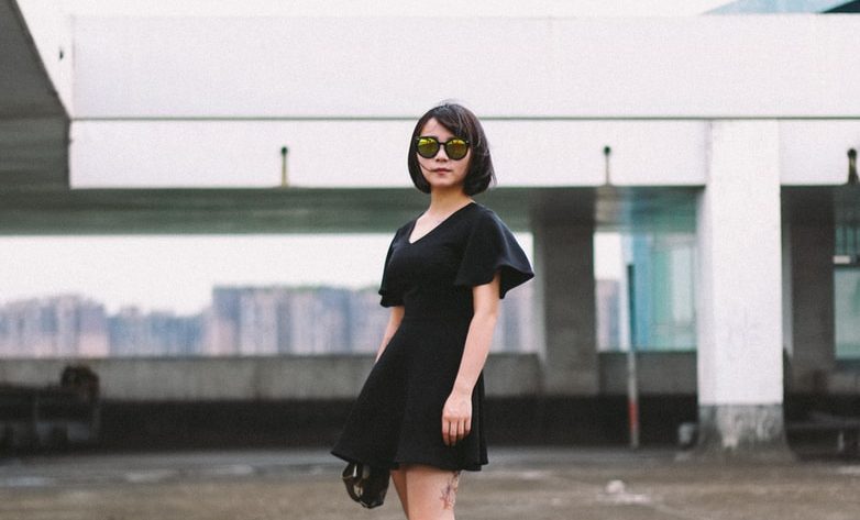 woman in black minidress and black sunglasses standing on street