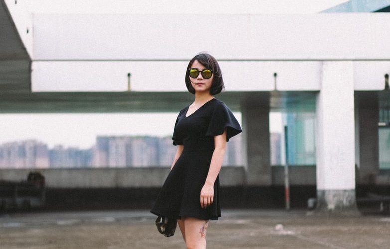 woman in black minidress and black sunglasses standing on street