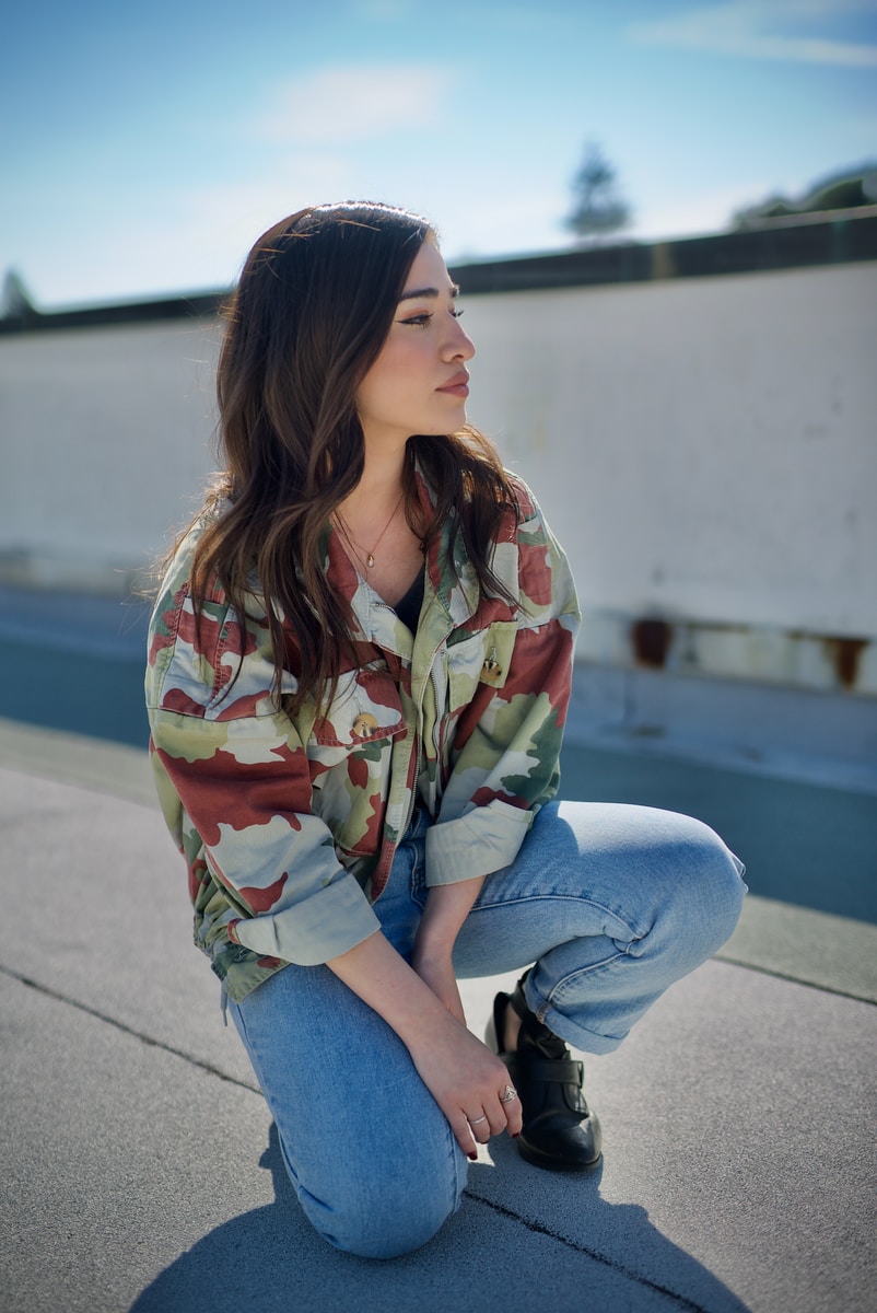 woman in blue denim jeans sitting on concrete floor during daytime
