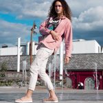 woman in pink jacket and white pants standing on gray concrete floor during daytime