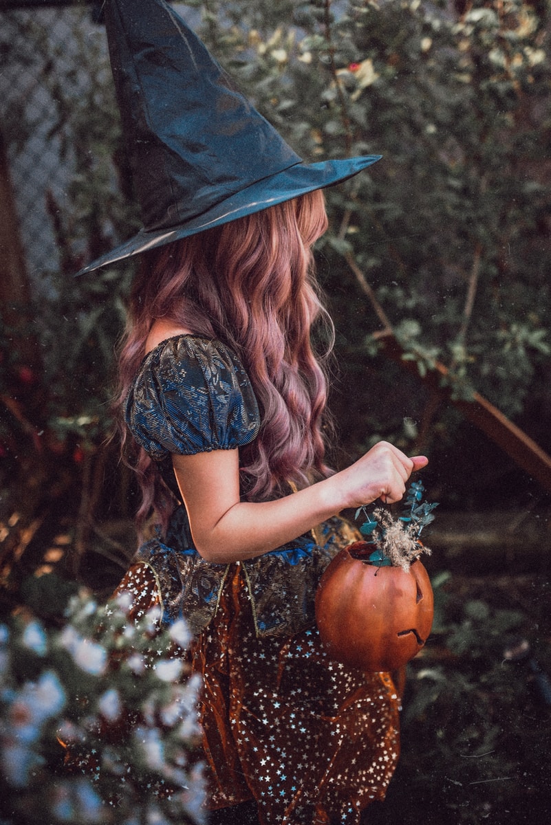 woman in black hat and brown dress holding pumpkin