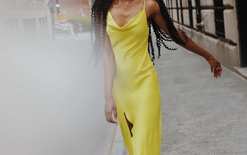 woman in yellow sleeveless dress standing on gray concrete pavement