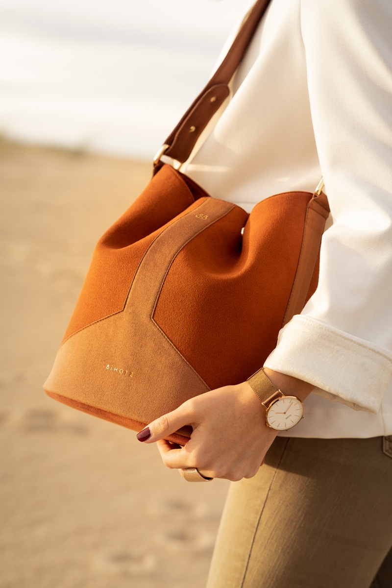person in white dress shirt holding brown leather handbag