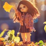 doll standing on brown leaves