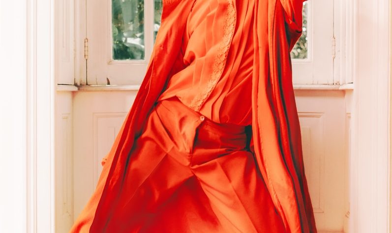 woman in orange long sleeve dress standing near window