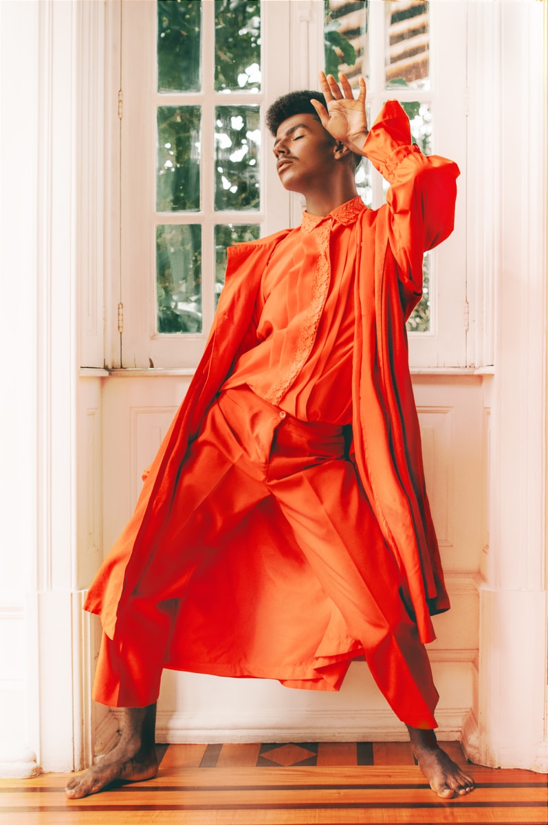 woman in orange long sleeve dress standing near window