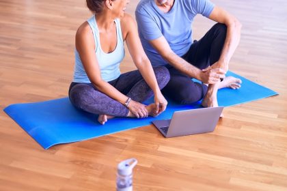 man in white tank top and gray pants sitting on blue yoga mat