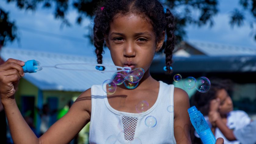 girl in white sleeveless top blowing bubbles