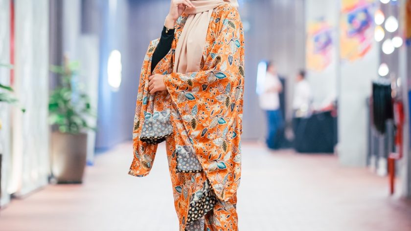 woman wearing orange and multicolored abaya dress standing and smiling