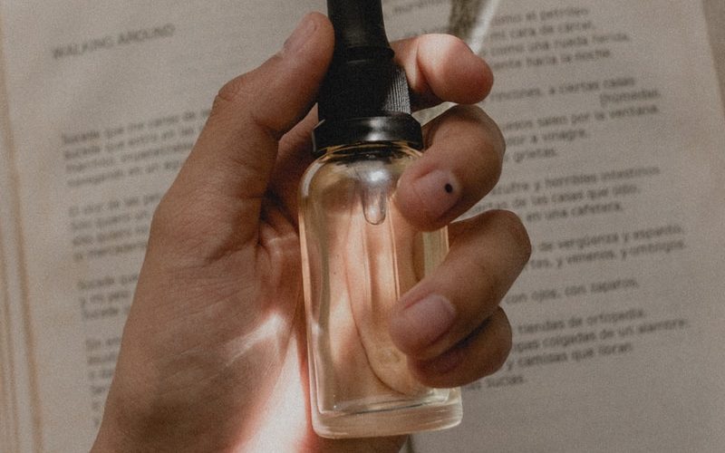 person holding small clear drop bottle